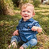 toddler, child, grass, outdoor, blue_shirt, jeans, barefoot, smile, happy, nature, sunlight, portrait, baby, sitting, greenery, casual_clothing, cute, young_child, daylight, relaxed