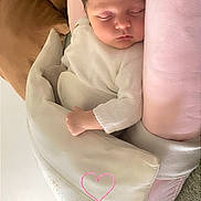 Romane a rejoint le concours — aidez-le/la à gagner de superbes lots ! baby, sleeping, infant, blanket, pink, white_clothing, cushion, cozy, peaceful, indoors, face, child, soft_texture, resting, newborn, cute, heart_doodle, blanket_pattern, carpet, furniture