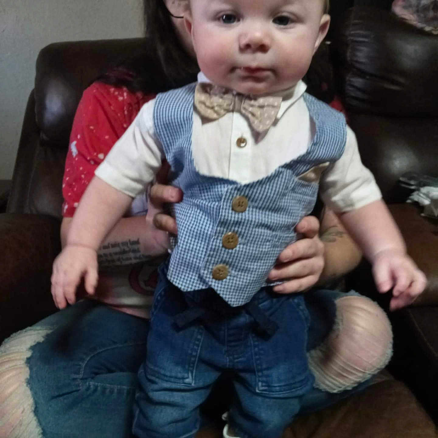 Brentley is registered to the contest to win money with this photo: accessories, baby, blazer, clothing, coat, couch, face, footwear, formalwear, furniture, head, jeans, pants, person, photography, portrait, shoe, sitting, tie, vest