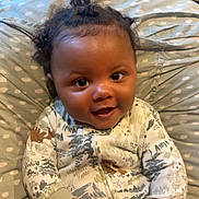 Jream joined the competition — help win amazing prizes! baby, child, smiling, onesie, hair_buns, cushion, polka_dot, indoor, cozy, patterned_clothing, happy, infant, person, cute, portrait, furniture, hand, face, sitting, comfort