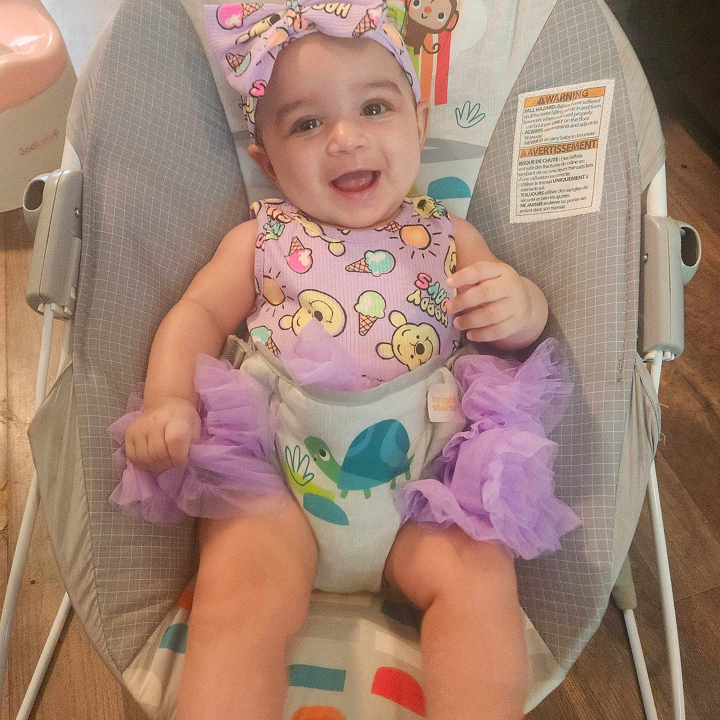 Trinity is registered to the contest to win money with this photo: animal_print, baby, bouncer, child, cute, face, happy, headband, indoor, infant, joyful, person, playful, purple_clothing, seat, sitting, smiling, toddler, tutu, wooden_floor