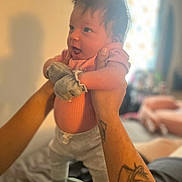 Joselynn joined the competition — help win amazing prizes! baby, infant, person, tattoo, hands, pink_clothing, mittens, holding, indoor, blurred_background, curious_expression, soft_lighting, cozy, home, portrait, child, cute, young, human, smiling