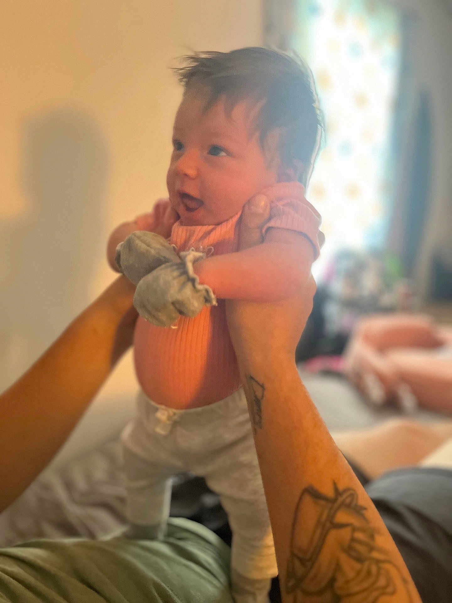 Joselynn joined the competition — help win amazing prizes! baby, infant, person, tattoo, hands, pink_clothing, mittens, holding, indoor, blurred_background, curious_expression, soft_lighting, cozy, home, portrait, child, cute, young, human, smiling