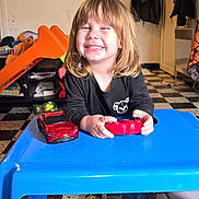 Sandro a rejoint le concours — aidez-le/la à gagner de superbes lots ! black_shirt, blonde_hair, blue_table, book, cartoon, child, coat, floor_tiles, furniture, happy, indoor, person, playing, red_toy_car, room, smiling, table, television, toy_controller, young