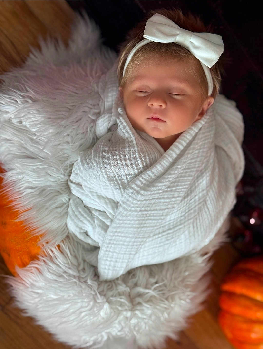 Evie is registered to the contest to win money with this photo: baby, sleeping, white_bow, headband, blanket, wrapped, fluffy_rug, pumpkin, autumn, cozy, soft_texture, infant, child, peaceful, indoors, portrait, cute, newborn, resting, warm
