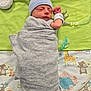 newborn, baby, swaddled, hat, blanket, pacifier, medical_tubes, hospital, sleeping, cute, infant, animal_print, green_cloth, gray, child, resting, soft, tiny, peaceful, wrapped