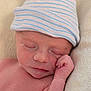 newborn, baby, infant, sleeping, hat, striped_hat, hand, closed_eyes, skin, face, resting, blanket, soft_texture, peaceful, cute, portrait, closeup, human, child, newborn_baby