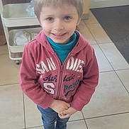 Arnaud a rejoint le concours — aidez-le/la à gagner de superbes lots ! child, boy, smiling, hoodie, striped_socks, indoor, tiled_floor, standing, hands_clasped, blue_eyes, short_hair, casual_clothing, home_interior, furniture, cart, floor_tiles, portrait, happy, young_child, cute