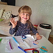 Clary participe au concours pour gagner de l'argent avec cette photo : child, girl, smiling, waving, craft, markers, paint, table, heart_shapes, paper, living_room, cushions, sofa, art, colorful, happy, indoor, person, hair, clothing