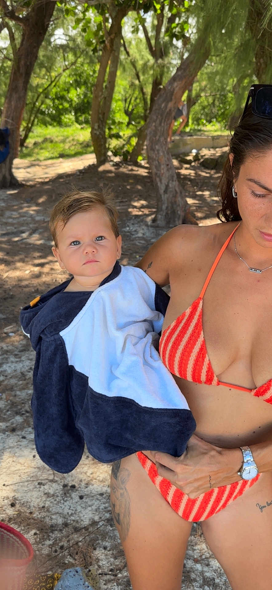 Maë a rejoint le concours — aidez-le/la à gagner de superbes lots ! baby, towel, woman, bikini, orange_stripes, outdoor, trees, sunlight, nature, tattoo, watch, summer, portrait, child, person, holding, shade, forest, skin, casual