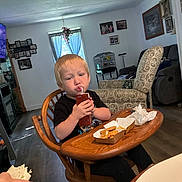 Hayse joined the competition — help win amazing prizes! child, toddler, young_person, sitting, high_chair, juice_box, straw, drinking, food, fried_food, meal, table, wooden_furniture, living_room, armchair, couch, window, curtains, family_home, portrait