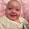 Embreigh is registered to the contest to win money with this photo: baby, infant, smile, tongue, face, eyes, onesie, clothing, pink, cushion, soft, happy, cute, child, portrait, indoors, skin, head, young, cozy