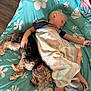 Colton is registered to the contest to win money with this photo: child, sleeping, dog, blanket, bed, rest, cozy, floral_pattern, teal, comfort, nap, pet, cuddling, indoors, relaxation, fur, hand, foot, animal, person