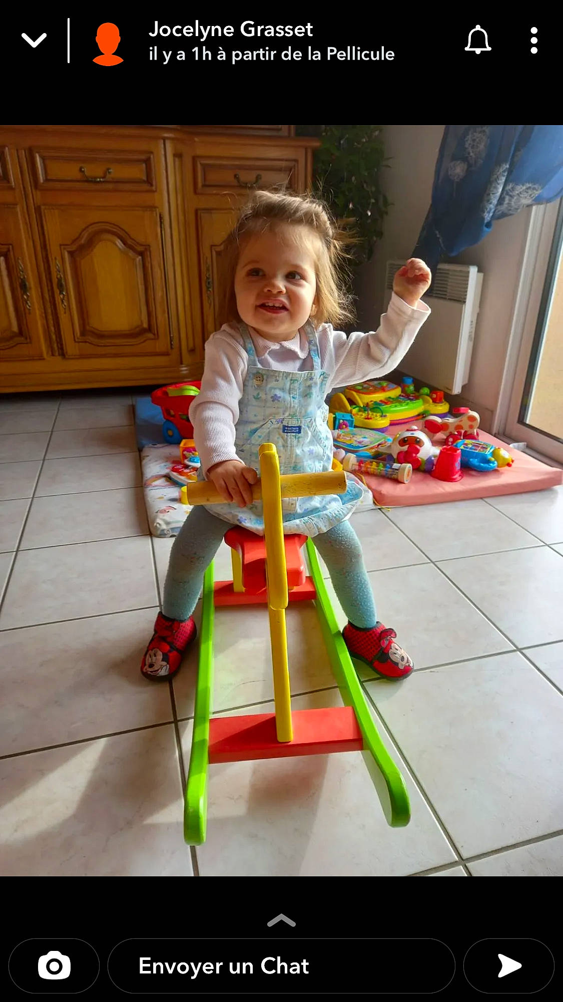 Maëva a rejoint le concours — aidez-le/la à gagner de superbes lots ! arm, baby_playing_with_toys, baby_toddler_clothing, cabinetry, chair, child, floor, flooring, hardwood, human_body, knee, leg, leisure, person, sitting, smile, t_shirt, toddler, toy, wood