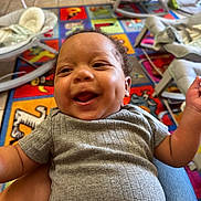 Ghalil joined the competition — help win amazing prizes! baby, background, child, clothing, colorful, curly_hair, dimple, floor, furniture, hand, happy, head, indoor, infant, person, playmat, seat, short_sleeve, smiling, tile