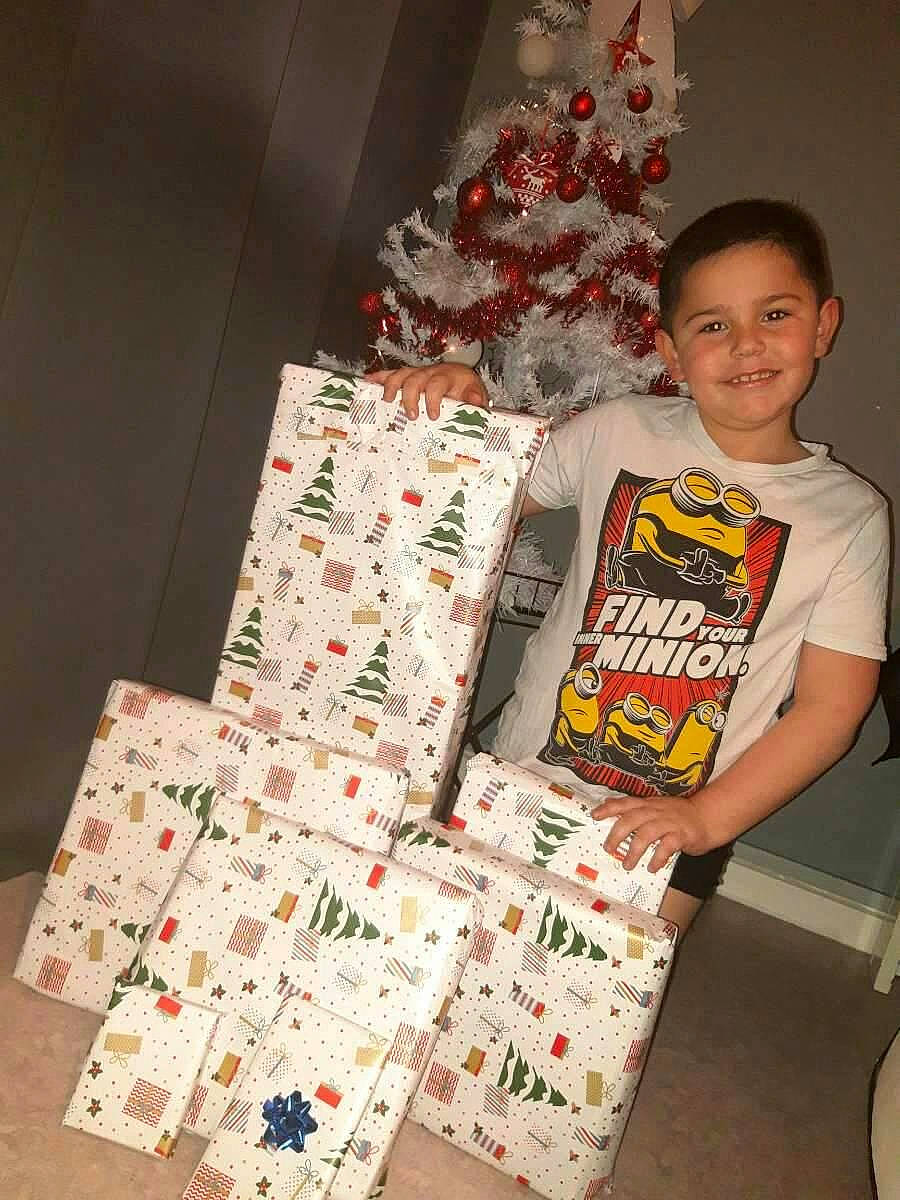 Youness a rejoint le concours — aidez-le/la à gagner de superbes lots ! box, carmine, child, christmas, christmas_decoration, christmas_ornament, christmas_tree, event, gift_wrapping, holiday, holiday_ornament, joy, lap, packing_materials, paper_product, pattern, person, red, room, shorts