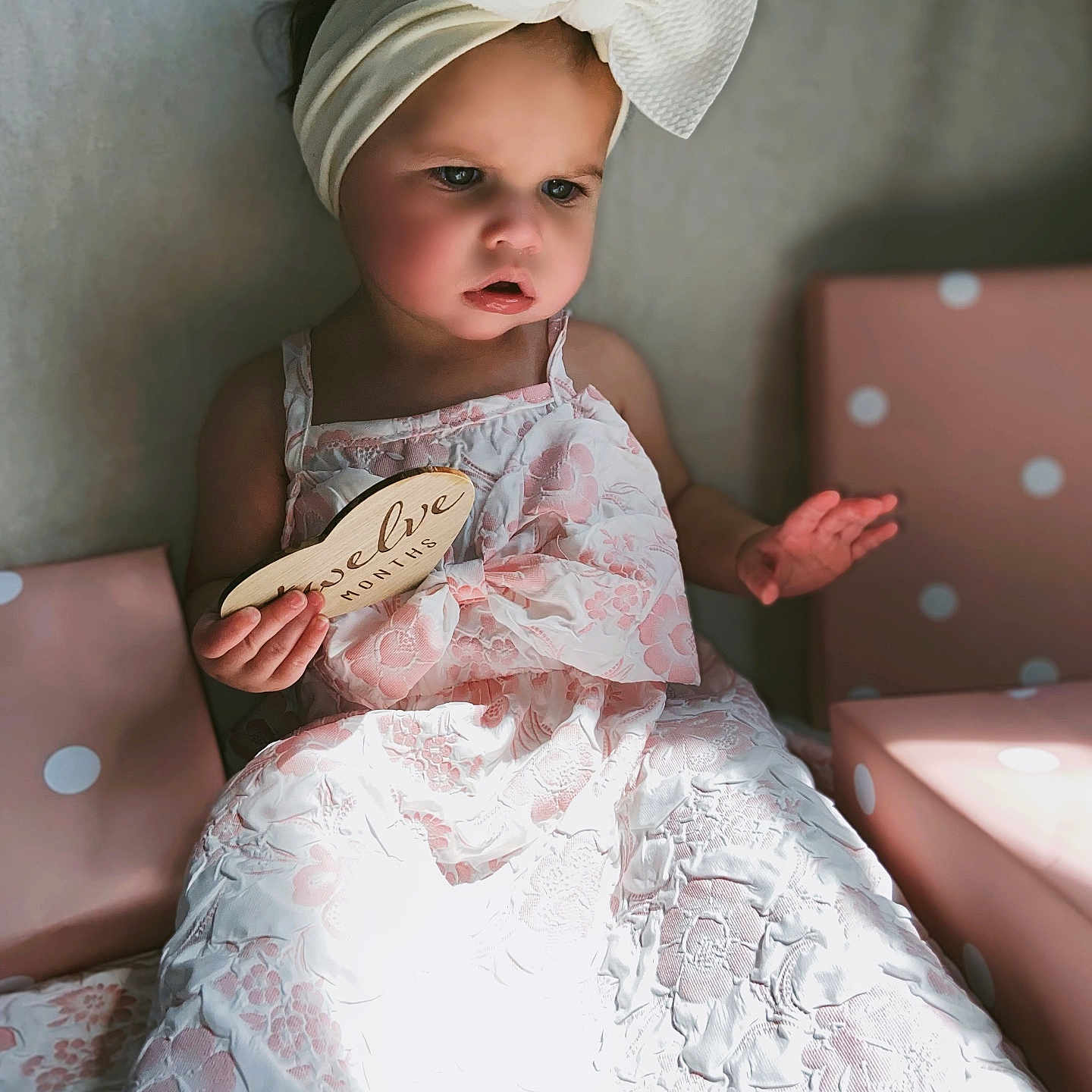Athena joined the competition — help win amazing prizes! toddler, child, baby, dress, headband, bow, pink, white, lace, gift_box, polka_dot, sign, wooden_sign, sitting, indoors, soft_light, portrait, cute, expression, hand