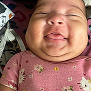 Evangeline is registered to the contest to win money with this photo: baby, infant, smiling, pink_clothing, hello_kitty, face, tongue_out, cheeks, cute, child, onesie, patterned_clothing, quilted_background, happy, close_up, person, portrait, sleepy_eyes, indoor, soft_light