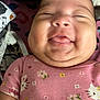 baby, infant, smiling, pink_clothing, hello_kitty, face, tongue_out, cheeks, cute, child, onesie, patterned_clothing, quilted_background, happy, close_up, person, portrait, sleepy_eyes, indoor, soft_light