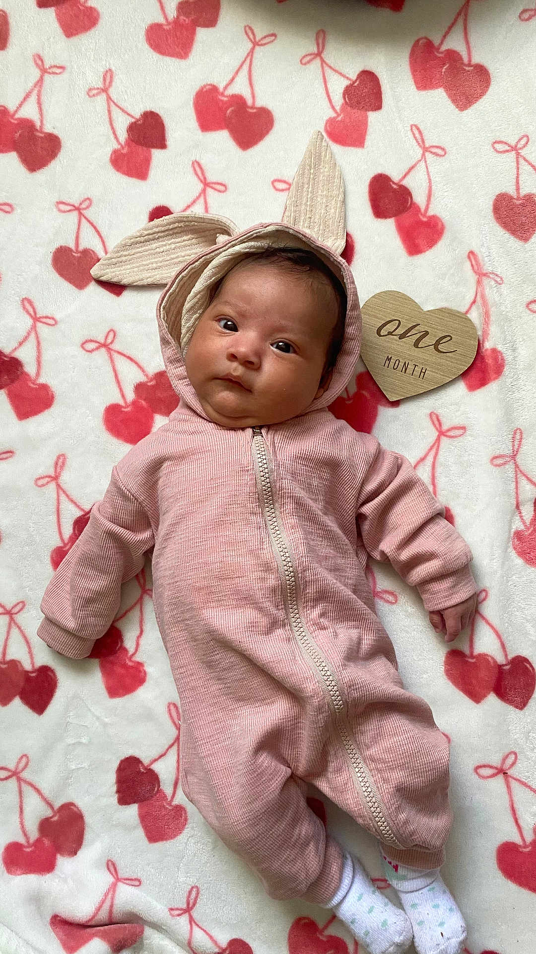 Evangeline joined the competition — help win amazing prizes! baby, infant, onesie, pink, bunny_ears, blanket, cherry_pattern, wooden_heart, one_month, cute, soft_texture, lying_down, newborn, child, portrait, socks, cozy, indoor, adorable, face