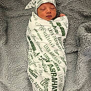 Liam is registered to the contest to win money with this photo: newborn, baby, swaddled, blanket, hat, sleeping, infant, soft_texture, personalized, name_print, cozy, resting, cute, portrait, child, fabric, comfort, bed, nursery, peaceful