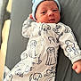 Liam joined the competition — help win amazing prizes! baby, newborn, infant, hat, onesie, dog_pattern, clothing, lying_down, gray_background, cute, small_hand, face, portrait, child, sleepwear, soft_lighting, indoors, cozy, baby_garment, adorable