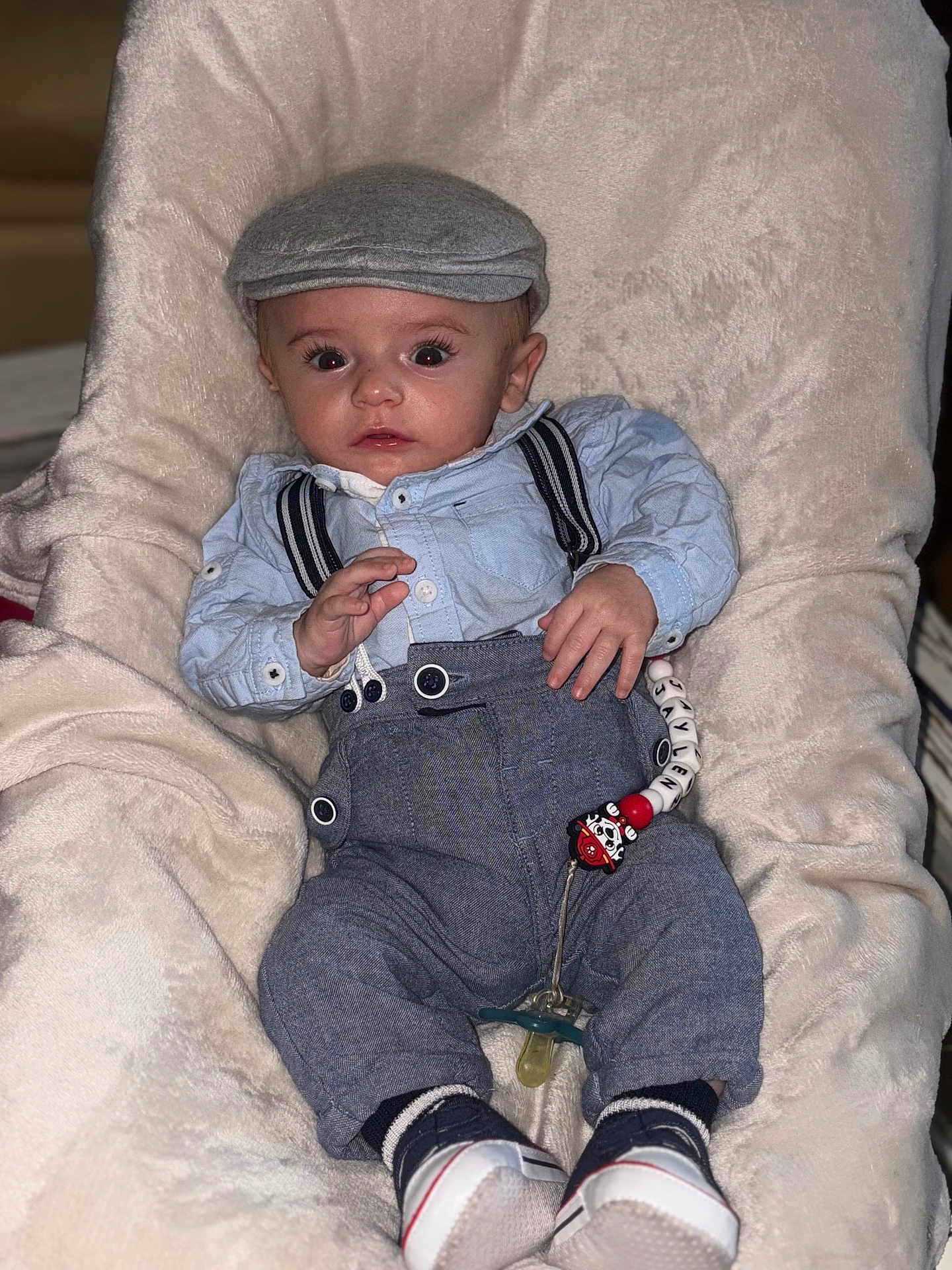 Jaylen participe au concours pour gagner de l'argent avec cette photo : accessory, baby, cap, child, clothing, cute, expression, face, fashion, hat, indoor, infant, pacifier, person, plush_chair, portrait, shoes, sitting, suspenders, young