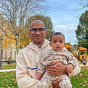 Brandon participe au concours pour gagner de l'argent avec cette photo : man, baby, child, glasses, hoodie, dinosaur_pattern, outdoor, park, grass, leaves, autumn, trees, playground, socks, holding, smiling, daytime, person, nature, casual_clothing