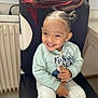 Maia participe au concours pour gagner de l'argent avec cette photo : blanket, casual_clothing, chair, child, cute, floor, hair_puffs, happy, home, indoor, person, radiator, seated, smiling, striped_pants, sweatshirt, toddler, tooth, window, young_child