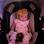 Serenity is registered to the contest to win money with this photo: baby, child, car_seat, yellow_bow, floral_outfit, socks, infant, striped_pattern, cute, indoors, portrait, seatbelt, warning_label, pink, cozy, looking, smirk, small_child, headwear, comfort