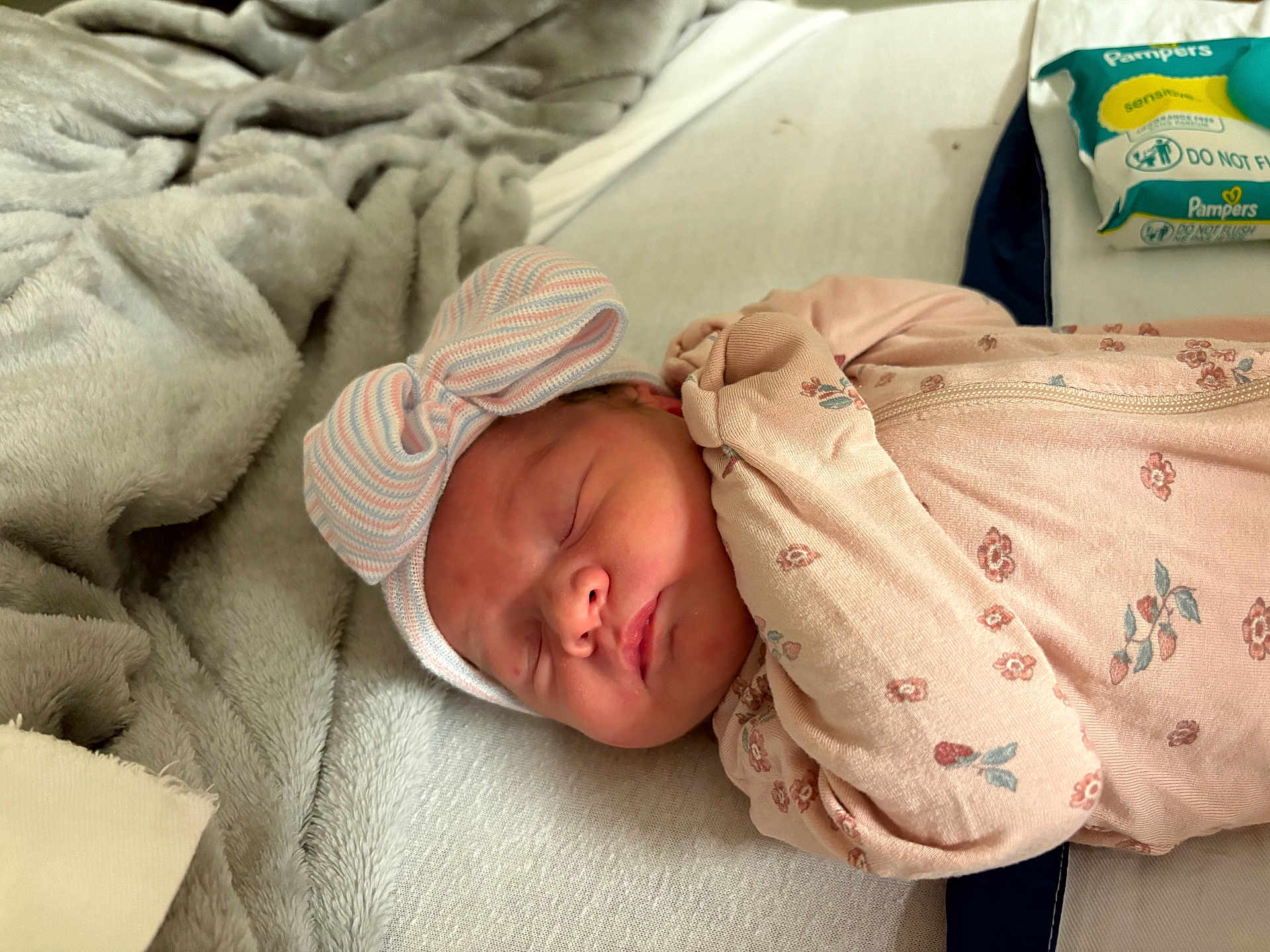 Emmalyn joined the competition — help win amazing prizes! baby, newborn, sleeping, bow_hat, floral_sleeper, blanket, bed, pampers, wipes, soft, cozy, infant, cute, peaceful, indoors, person, face, headwear, resting, child