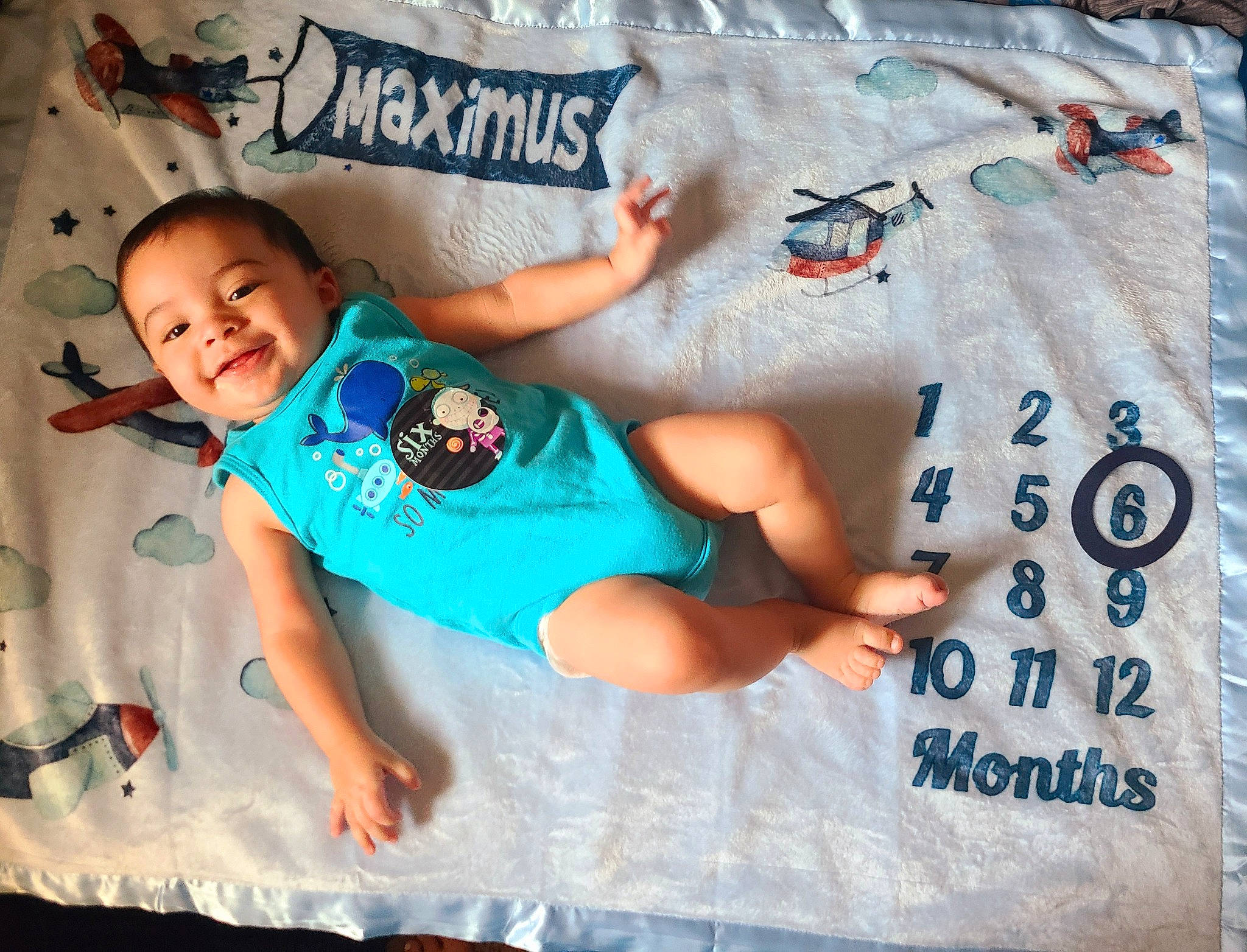 Maximus is registered to the contest to win money with this photo: azure, baby, baby_toddler_clothing, comfort, font, fun, happy, joy, leisure, linens, pattern, person, recreation, shorts, sitting, sleeve, smile, t_shirt, textile, thigh