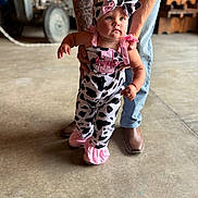Brynnlee is registered to the contest to win money with this photo: baby, child, cow_print, pink, headband, tattoo, adult, jeans, boots, tractor, barn, floor, person, helping, walking, cute, indoor, clothing, hold, support