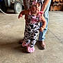 baby, child, cow_print, pink, headband, tattoo, adult, jeans, boots, tractor, barn, floor, person, helping, walking, cute, indoor, clothing, hold, support