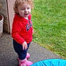 toddler, child, red_hoodie, pink_boots, curly_hair, trampoline, outdoor, grass, patio, concrete, play, happy, smiling, person, casual_clothing, daylight, fun, young_child, garden, curious