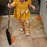 Alysia is registered to the contest to win money with this photo: child, toddler, broom, floor, tile_floor, yellow_clothing, indoor, kitchen, cleaning, person, carpet, cabinet, door, toy, home, pants, footwear, hair, cute, activity