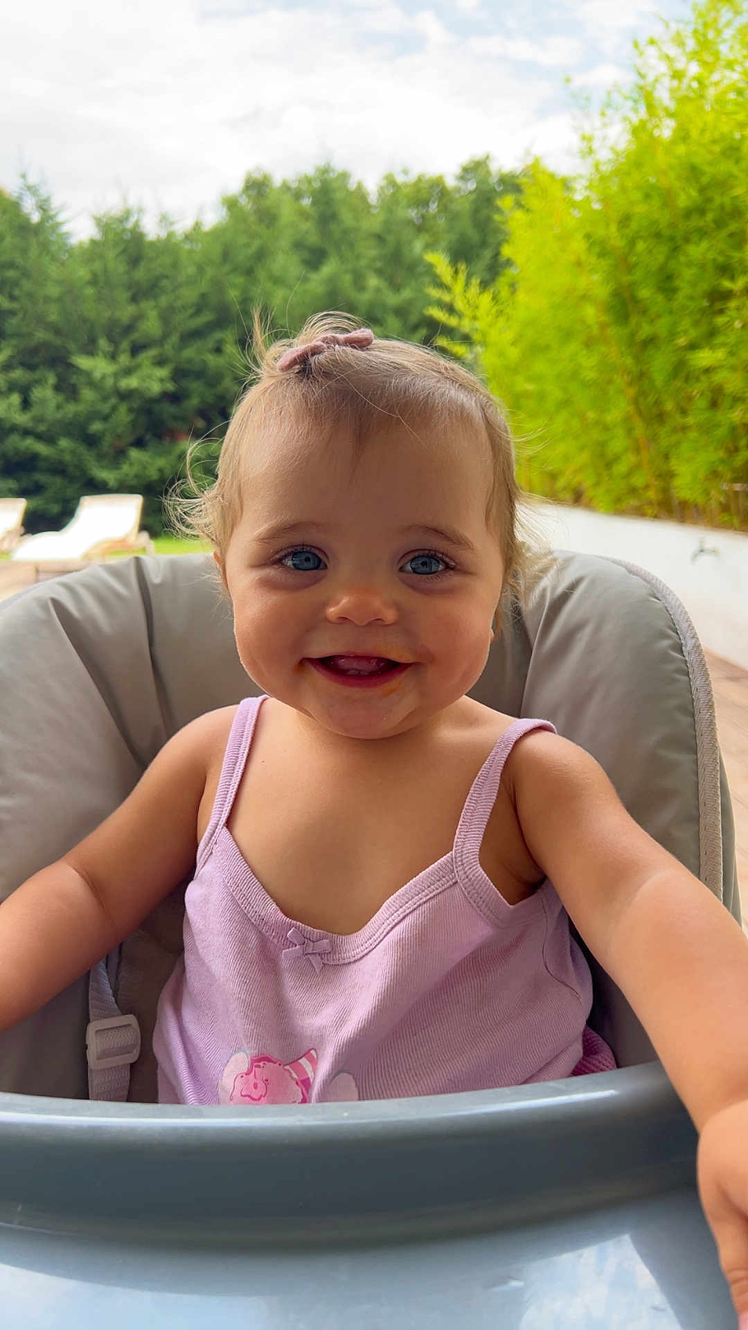 Chiara a rejoint le concours — aidez-le/la à gagner de superbes lots ! child, toddler, baby, smiling, high_chair, outdoor, greenery, nature, happy, face, blue_eyes, hair_bow, tank_top, summer, portrait, cute, daylight, garden, expression, skin