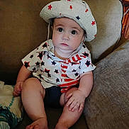 Elijah is registered to the contest to win money with this photo: baby, child, infant, couch, hat, clothing, stars, stripes, sitting, indoors, cute, portrait, face, hand, foot, furniture, expression, young, person, apparel