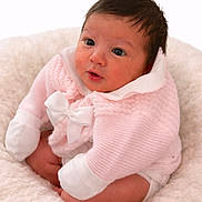 Vienna is registered to the contest to win money with this photo: baby, infant, pink_clothing, white_bow, knitwear, fluffy_blanket, cute, portrait, child, sitting, soft_texture, indoor, young, adorable, face, expression, curious, cozy, warm, small