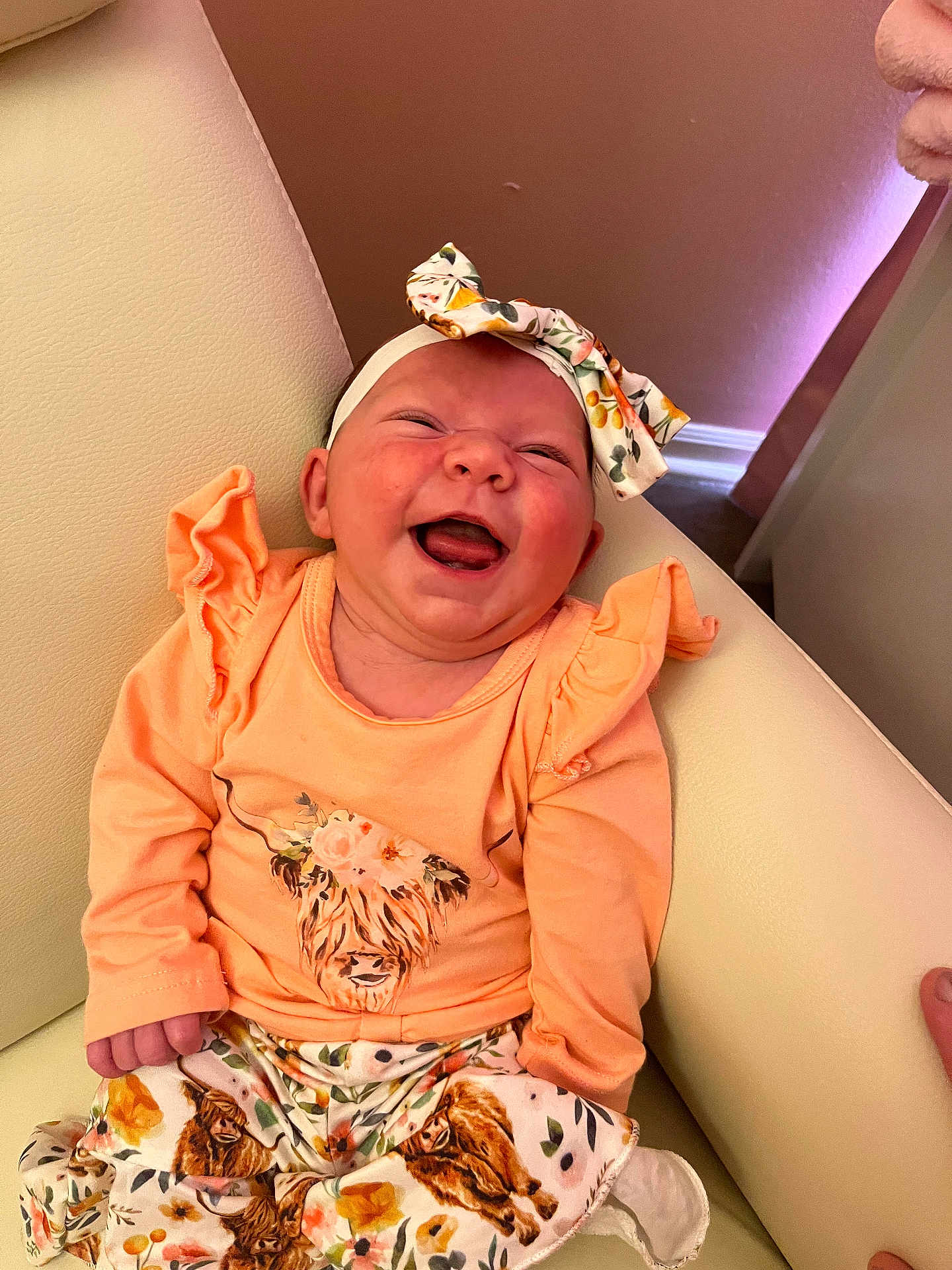 Isabella joined the competition — help win amazing prizes! baby, smiling, infant, headband, orange_clothing, sitting, couch, indoor, happy, portrait, child, cute, apparel, patterned_pants, flower, furniture, skin, tongue_out, head, person