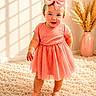 Isabella joined the competition — help win amazing prizes! baby, barefoot, bow, carpet, child, cute, decor, fashion, happy, home, indoor, pampas_grass, pink_dress, portrait, smiling, soft_light, standing, sunlight, toddler, vase