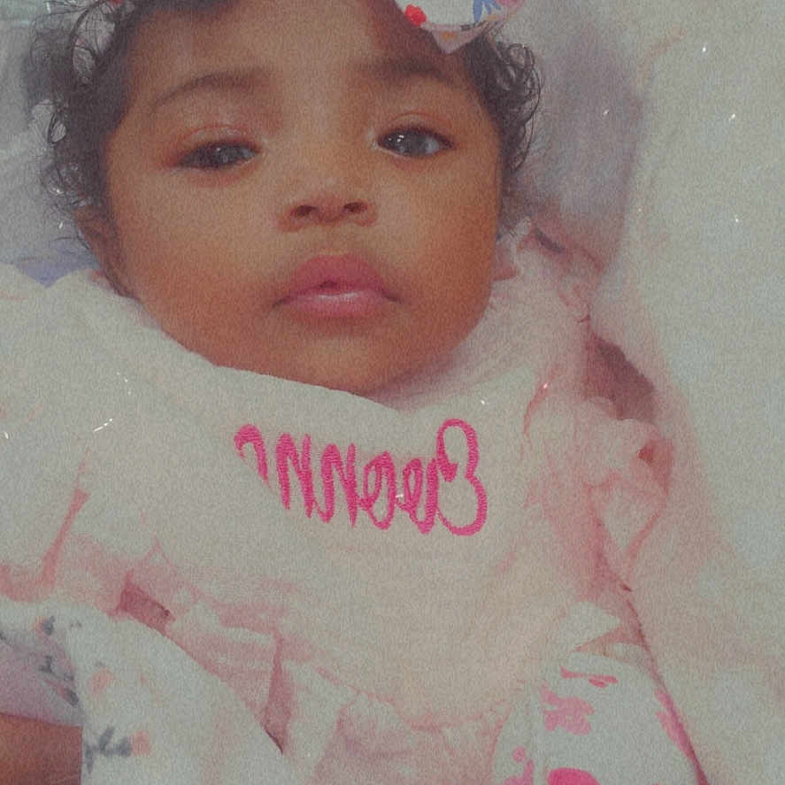 Evonna is registered to the contest to win money with this photo: baby, blanket, bow, child, clothing, cozy, curly_hair, cute, face, flower, gaze, headband, indoors, infant, pattern, person, pink, portrait, soft_lighting, wrapped