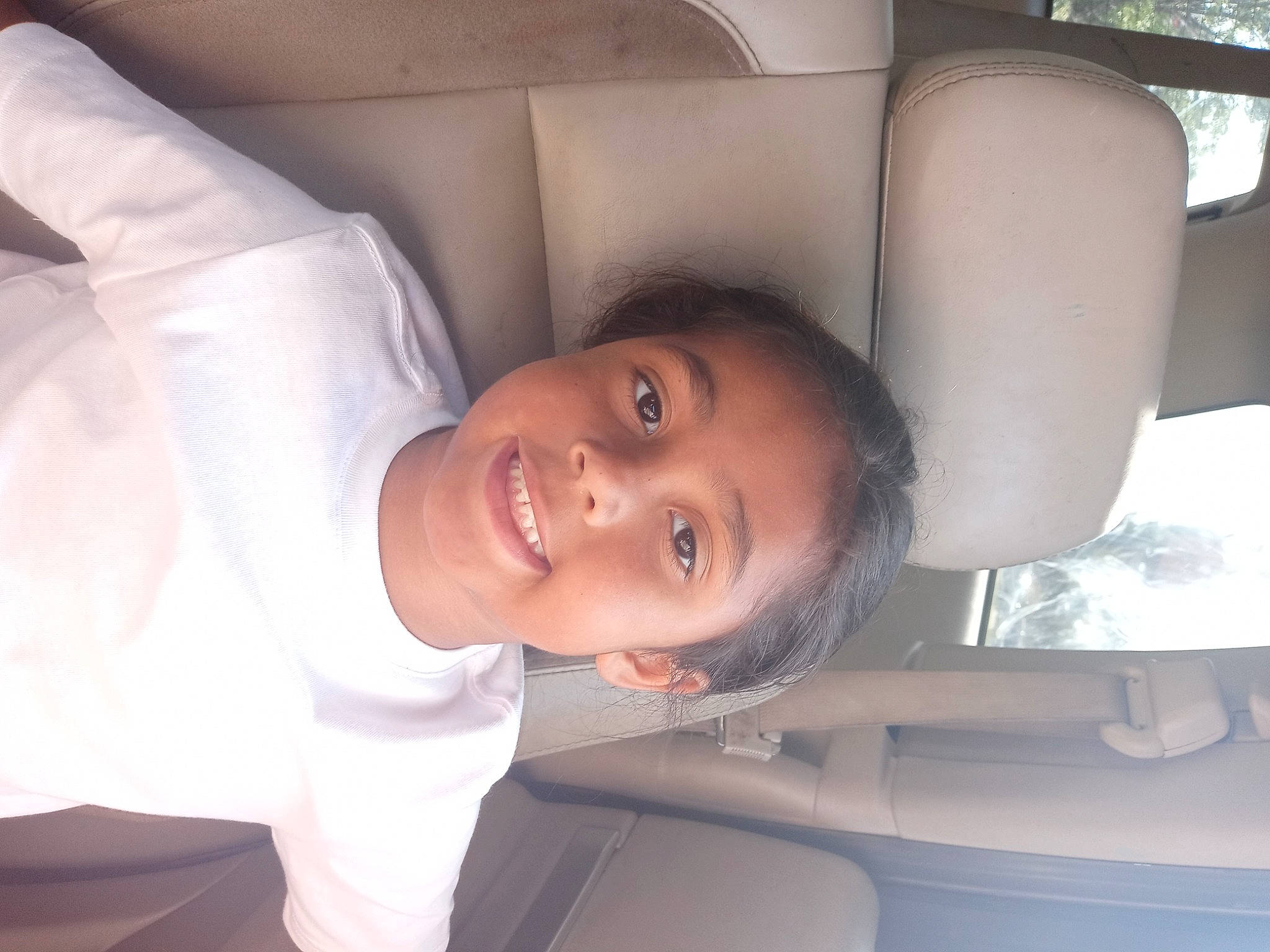 Hezekiah is registered to the contest to win money with this photo: arm, auto_part, automotive_design, automotive_exterior, car, car_seat, comfort, eyebrow, fun, happy, jaw, joy, lip, mouth, nose, person, skin, smile, toddler, tree