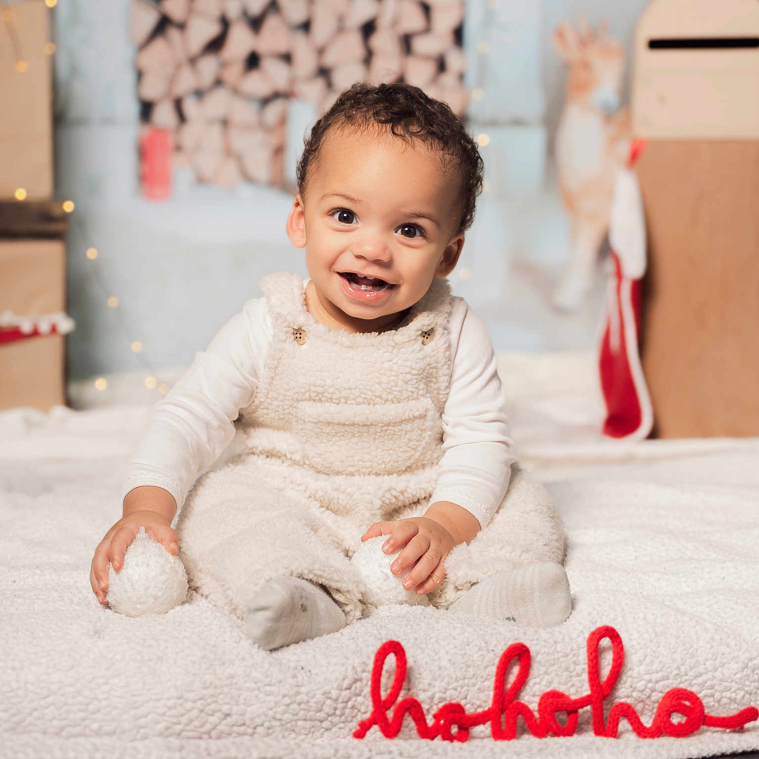 Swann participe au concours pour gagner de l'argent avec cette photo : baby, blanket, child, christmas, cozy, cute, festive, firewood, floor, happy, holiday_decor, indoors, portrait, red_text, sitting, smiling, soft_toys, toddler, warm_lighting, white_clothing