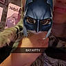 Tiki joined the competition — help win amazing prizes! cat, person, mask, batman, face_filter, indoor, poster, hand, holding, animal, pet, funny, smile, dark, wall, shirt, text_overlay, closeup, costume, filter