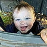 blue_eyes, casual_clothing, child, close_up, curious, daylight, dirt, face, grass, hair, hand, happy, joy, natural_light, outdoor, person, playful, smiling, toddler, young_child