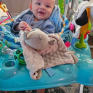 Gunnar joined the competition — help win amazing prizes! baby, infant, smiling, plush_toy, baby_activity_center, indoor, child, happy, seated, clothing, toy, floor, carpet, blanket, person, face, head, cute, playtime, young_child