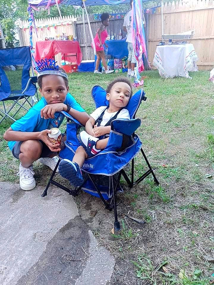 Michael is registered to the contest to win money with this photo: camping, chair, child, event, folding_chair, fun, furniture, garden, grass, leisure, outdoor_furniture, person, plant, pole, recreation, shade, shorts, sitting, smile, tent