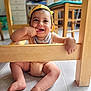 baby, cap, child, cute, feet, finger_in_mouth, floor, furniture, happy, home, indoor, infant, legs, natural_light, person, playing, portrait, sitting, smile, wooden_table
