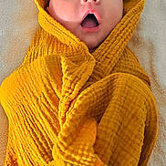 Lou participe au concours pour gagner de l'argent avec cette photo : baby, child, blanket, yellow, wrapped, surprised, expression, face, head, mouth_open, eyes, texture, soft, towel, infant, cute, portrait, laying_down, fabric, cozy